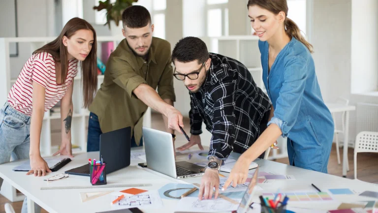 young-creative-people-with-laptop-sketches-discussing-new-project-together-group-guys-gals-working-modern-cozy-office